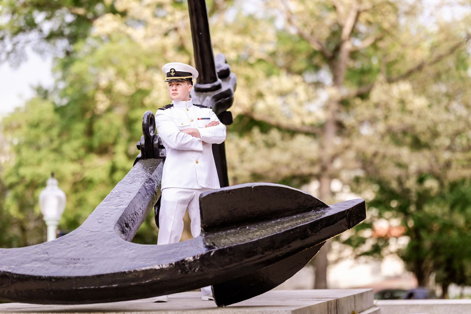 A large decorative black anchor monument sits in a park surrounded by green trees on a sunny day.