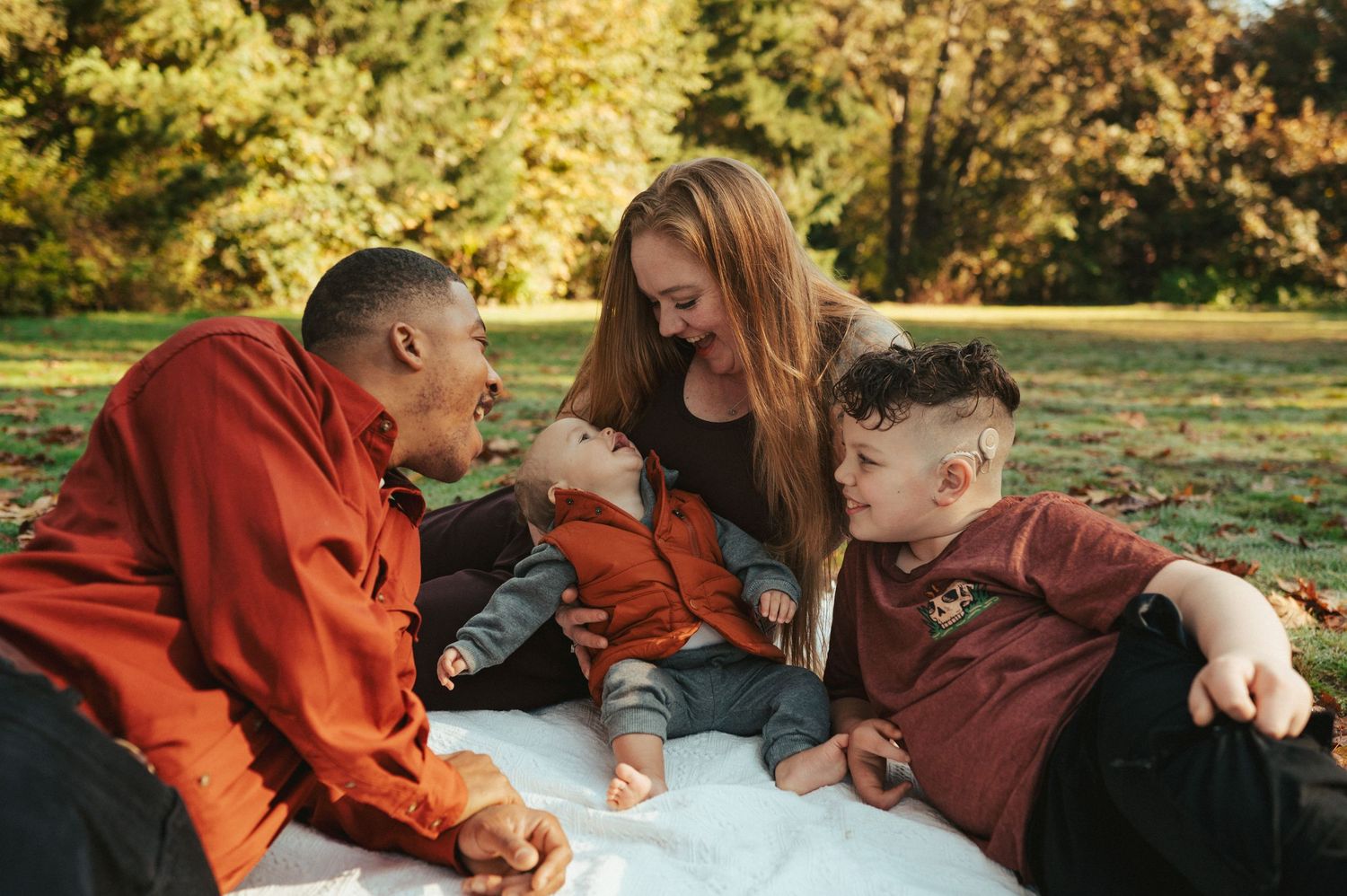 A family having an enjoyable picnic together on a blanket during an autumn day in a park with golden foliage.