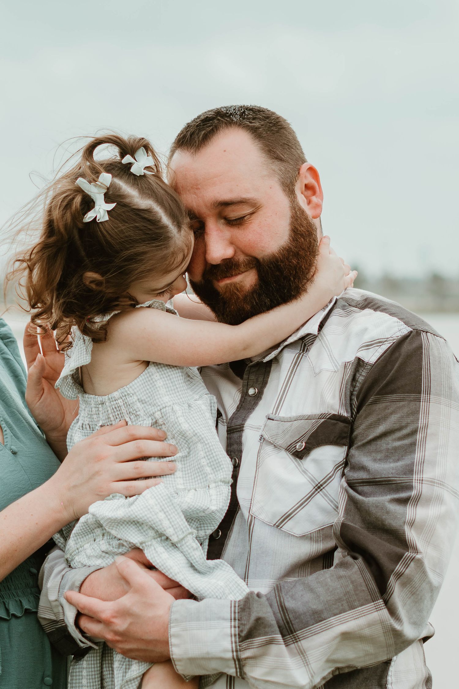 A sweet tender moment outdoors as a small girl in a lace dress embraces someone in a denim jacket.