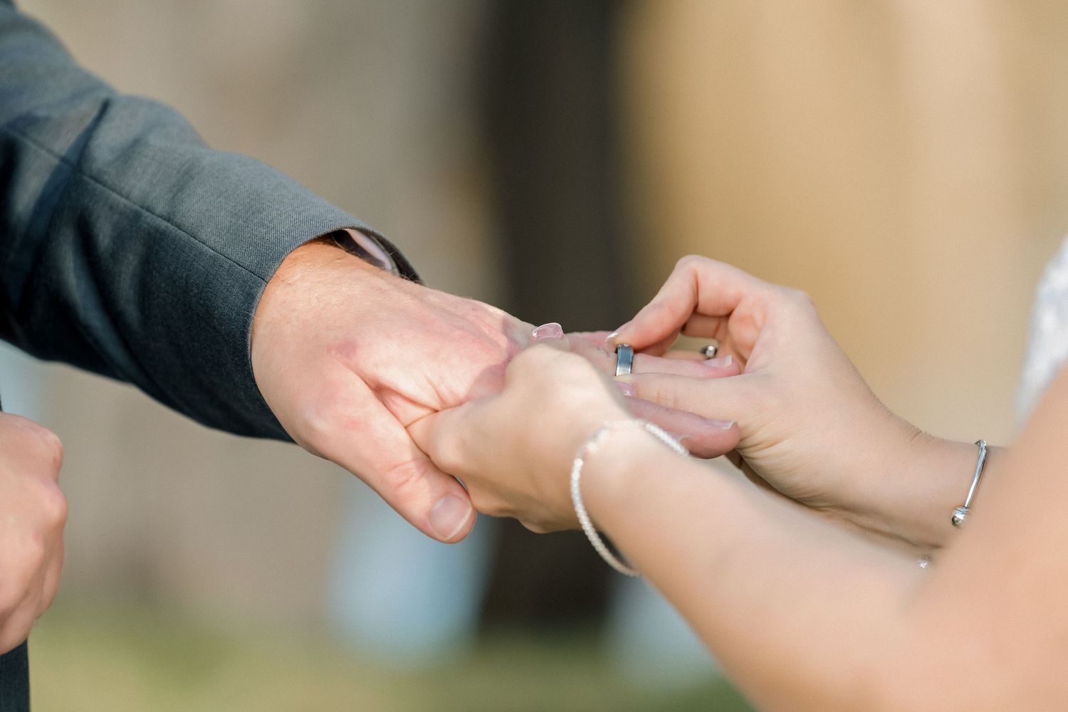 Close-up of a groom placing a wedding ring on the bride's finger during a wedding ceremony.