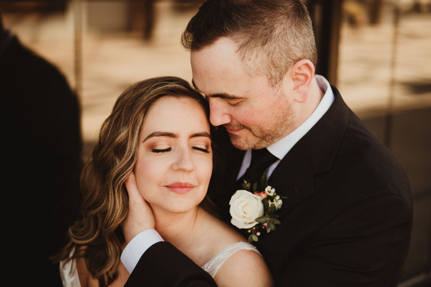 A romantic wedding portrait showing an intimate moment in warm lighting.