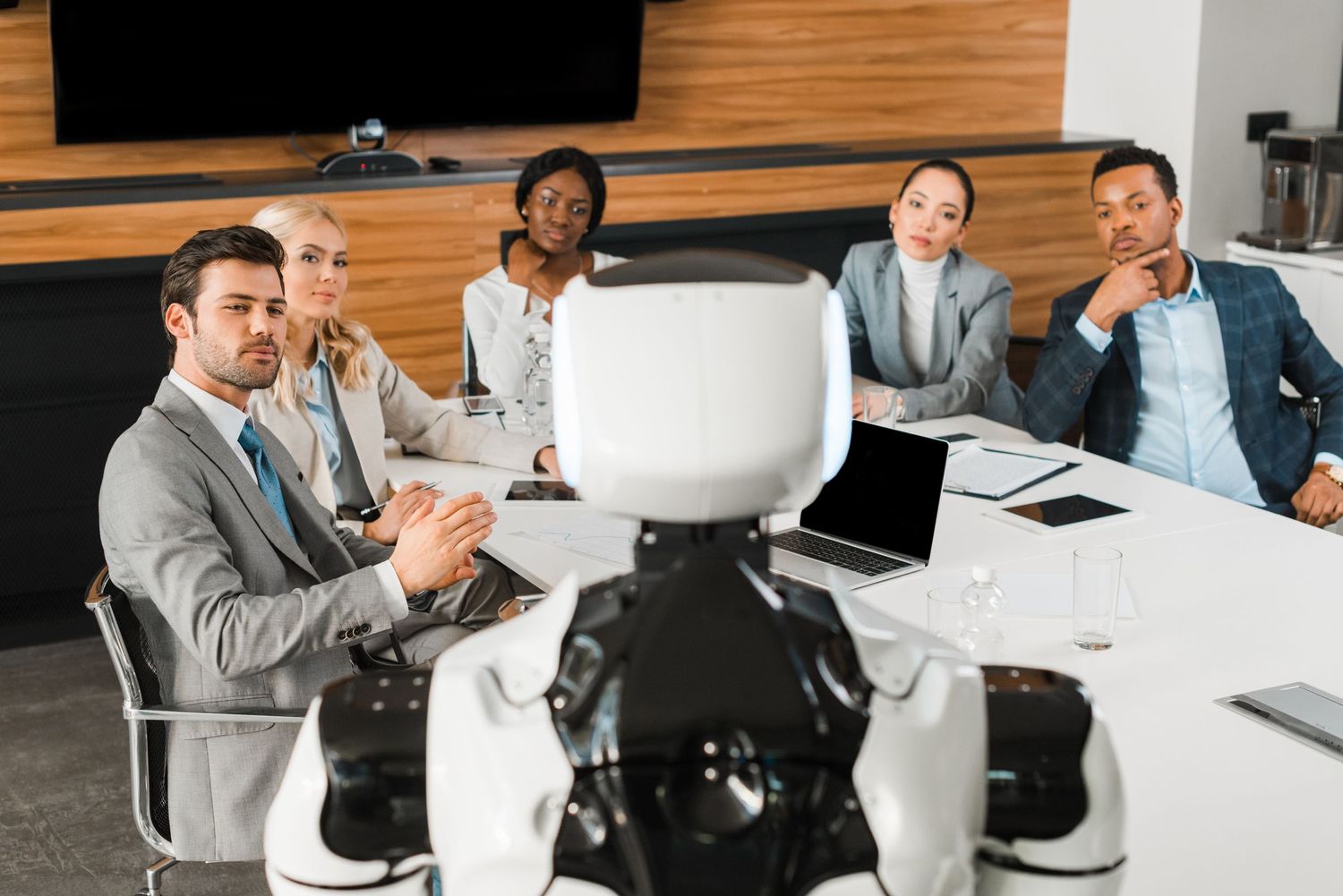 Business colleagues in suits sitting at conference table during corporate meeting in modern office.