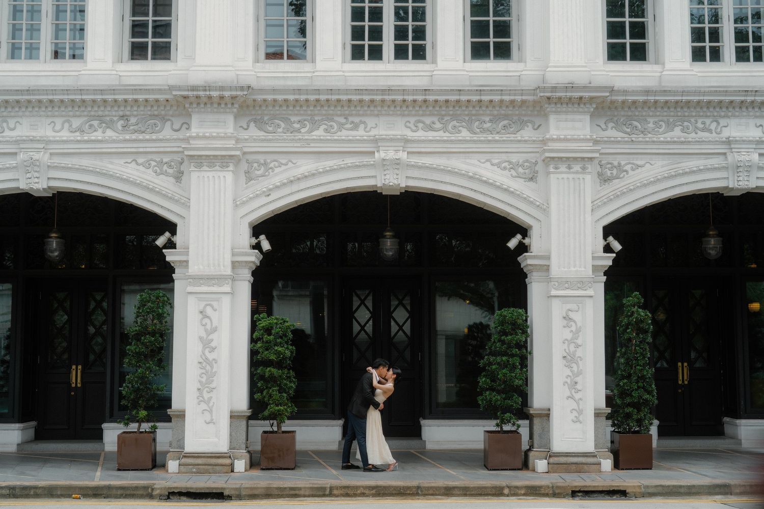 White arched colonnade with ornate architectural details forms a symmetric walkway along a historic building facade.