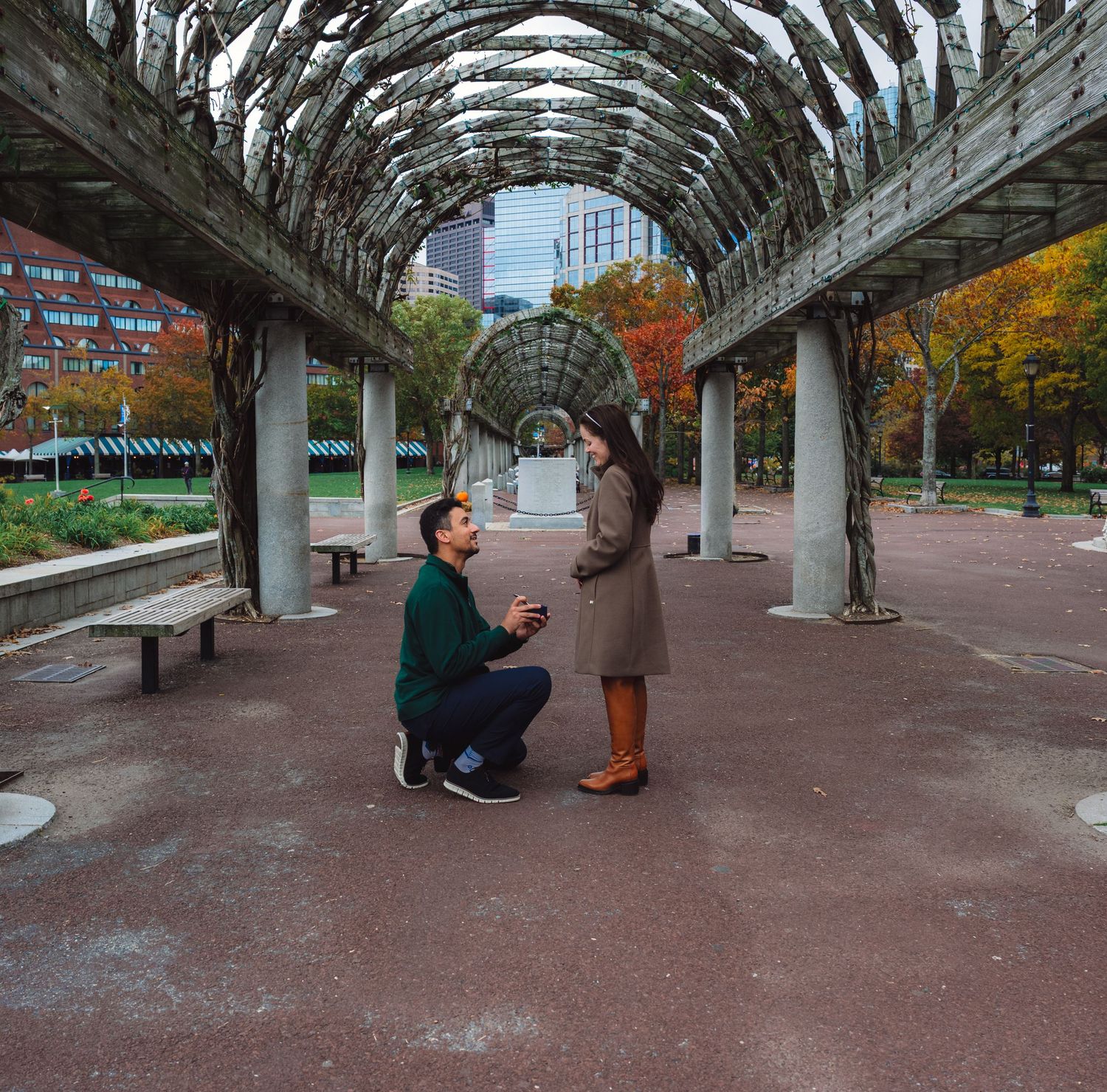 A special moment captured under a curved pergola with fall foliage in the background.