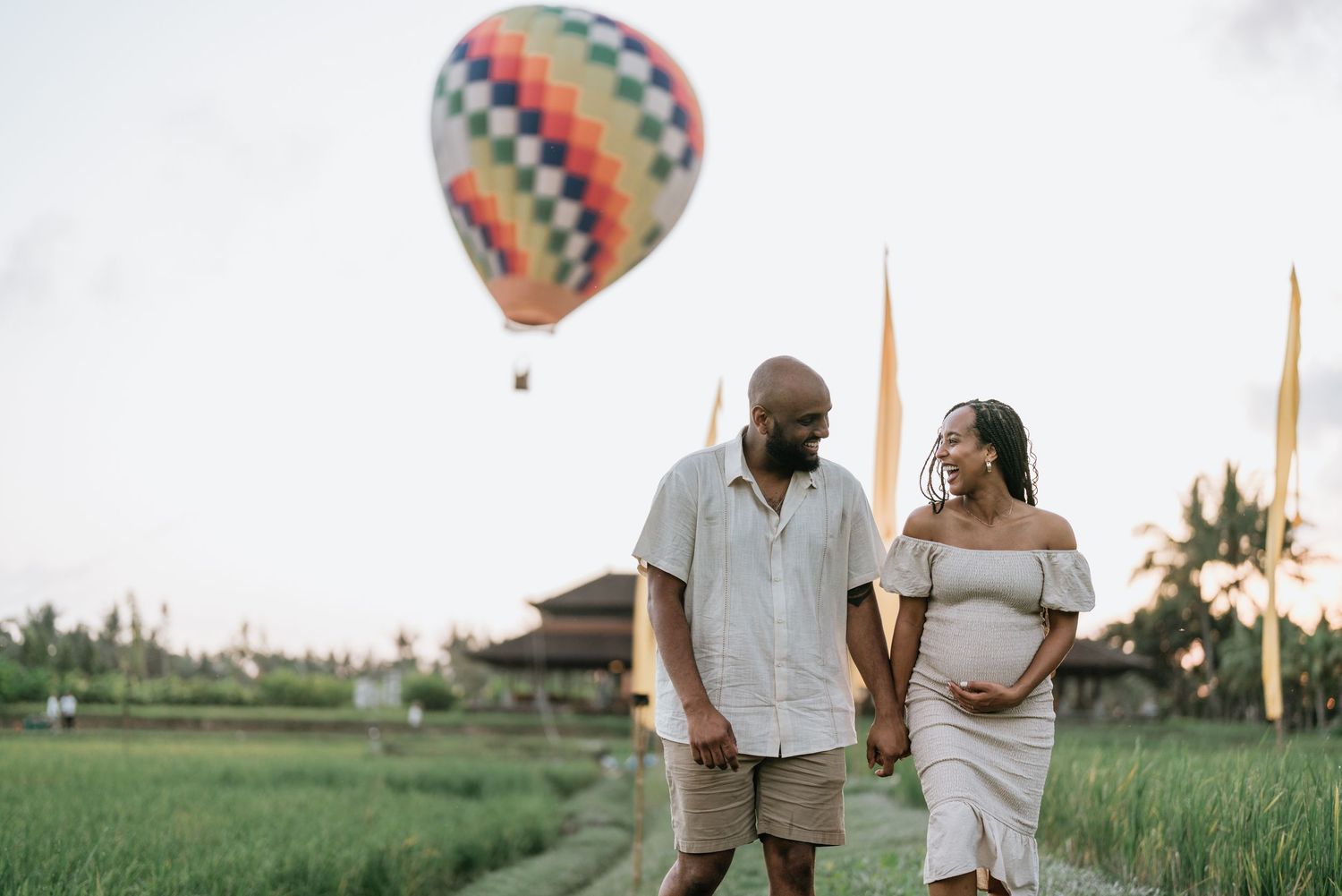 Family playing and dancing together in a lush green rice field at sunset.