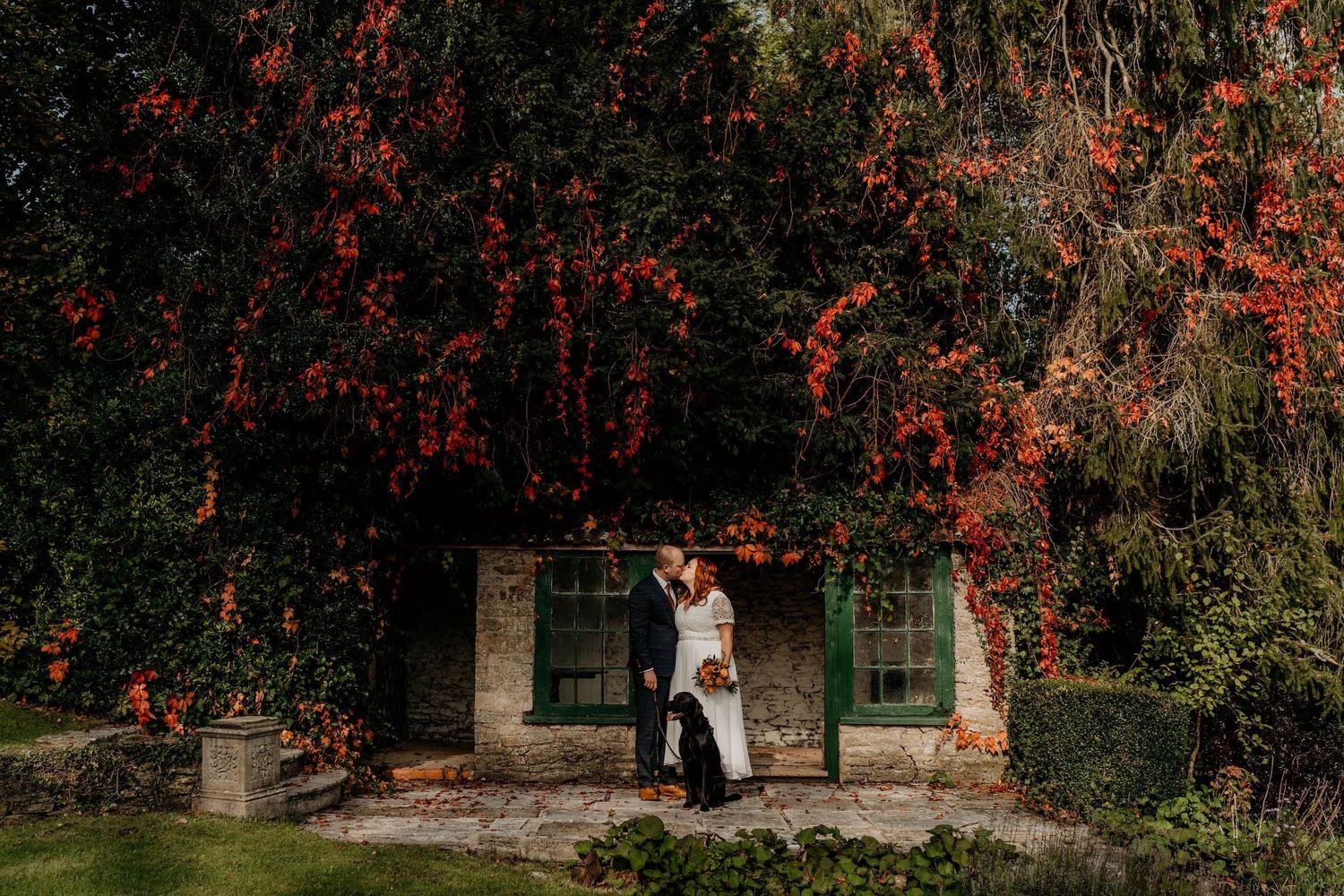 Wedding ceremony setup in rustic wooden barn with white floral arrangements and natural lighting.