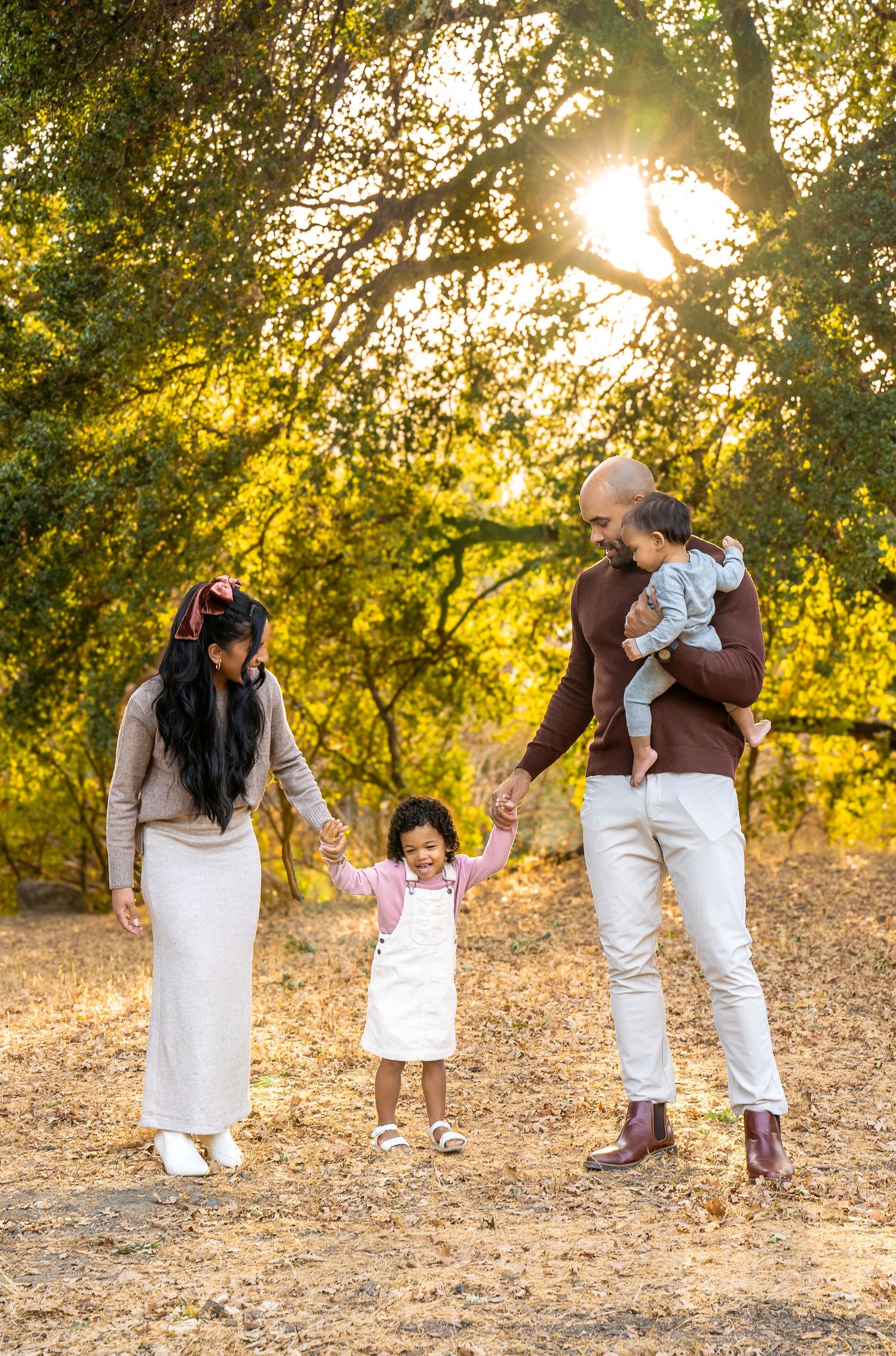 Sweet dance sequence of parent and child holding hands outdoors at sunset with warm golden light filtering through trees.