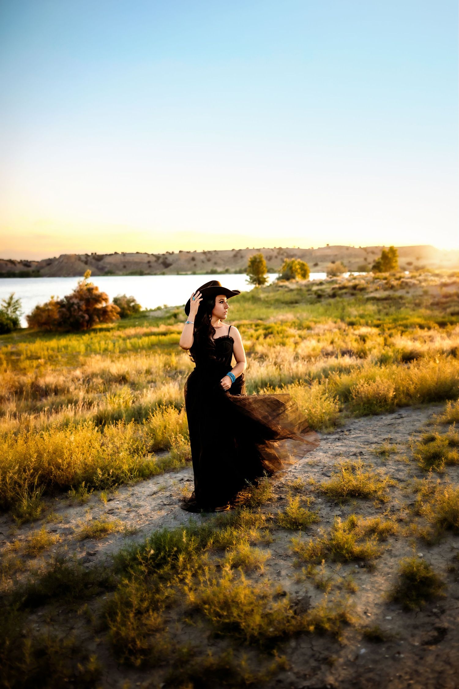 Silhouetted figures standing in golden grassland at sunset with soft light illuminating the arid landscape.