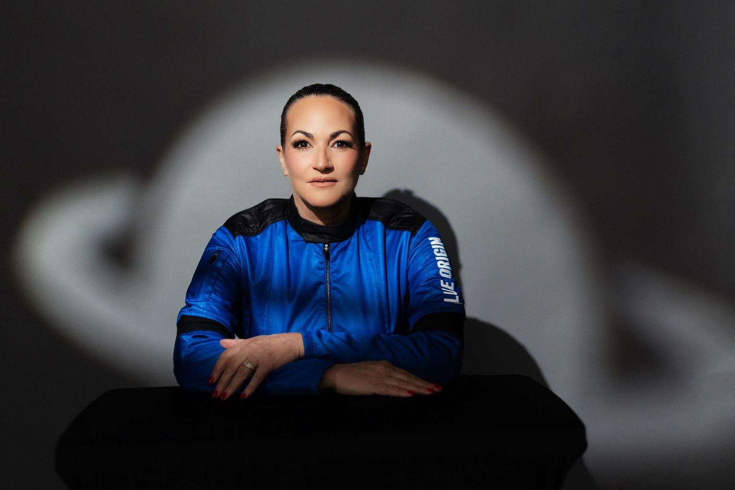 A person in a bright blue hoodie poses against a dark background in a portrait photo series.