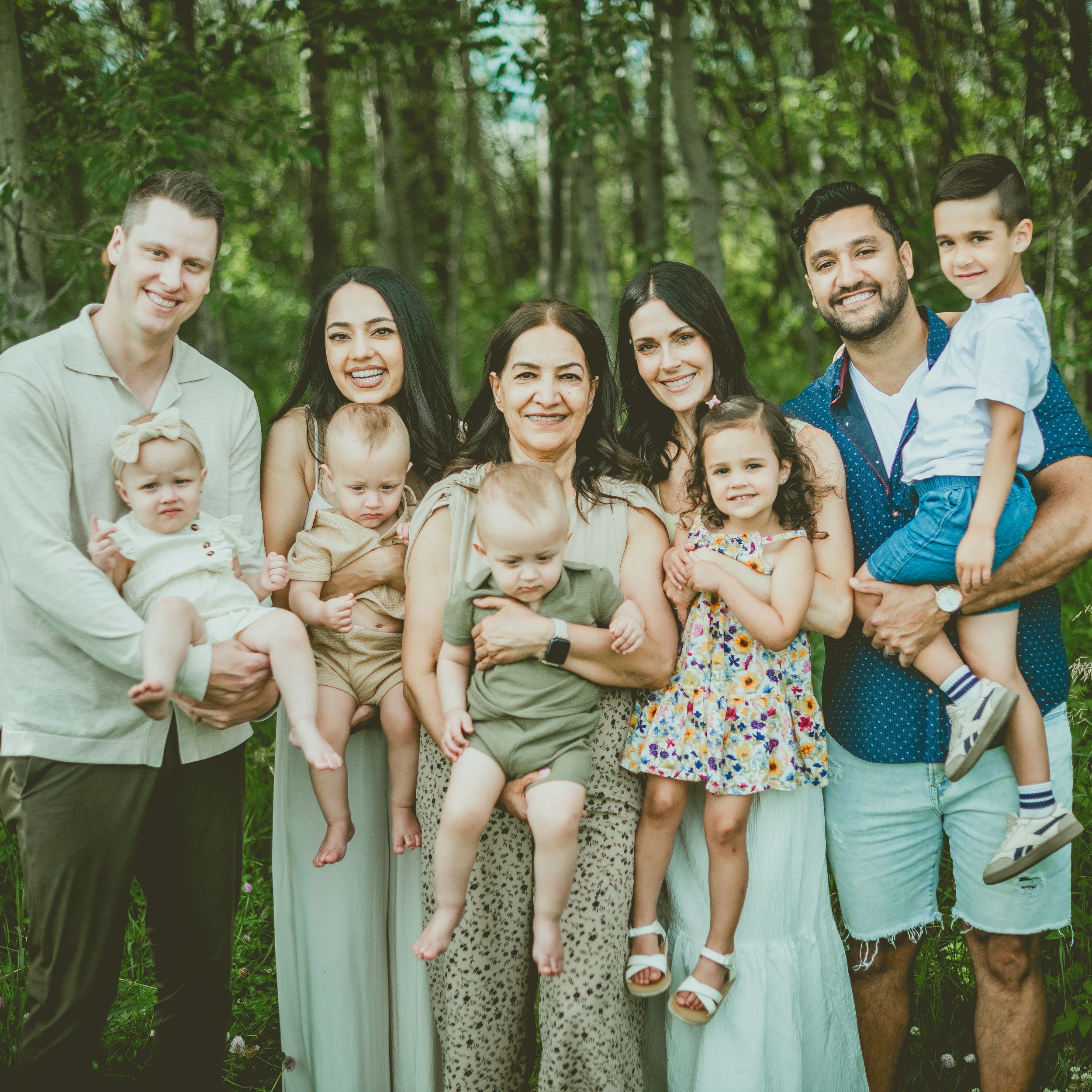 A group poses together outdoors in St Albert in coordinated pastel outfits for a casual family photo session in a natural setting.