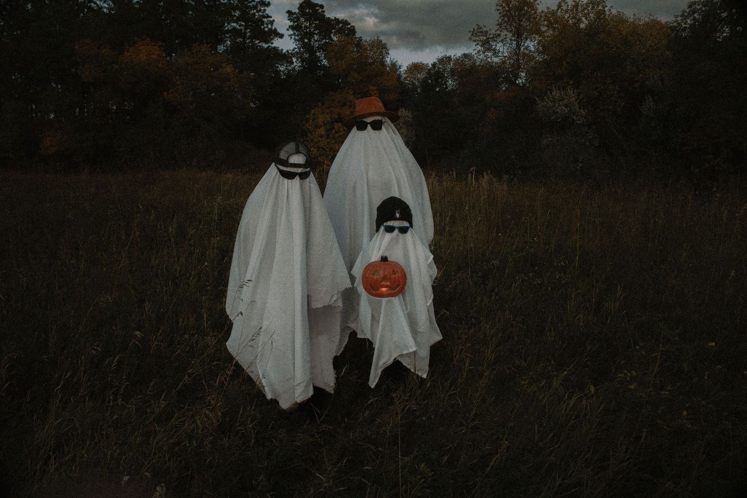 Three ghost figures in white sheets walk together in a spooky dark field at dusk. Garrison, ND