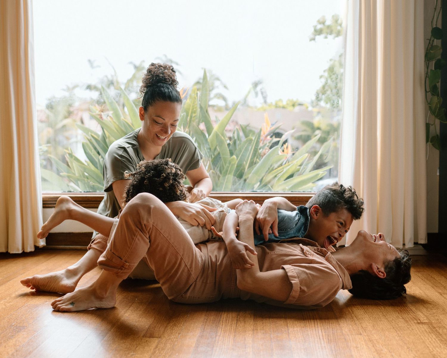 A person and child lie on a wooden floor in gentle natural light while reading a book together.
