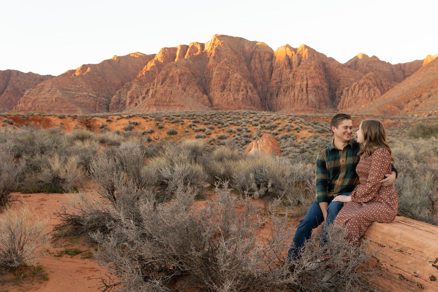 kayenta ivins outside St. George utah man and woman sitting holding each other looking at each other with the red mountain in the background