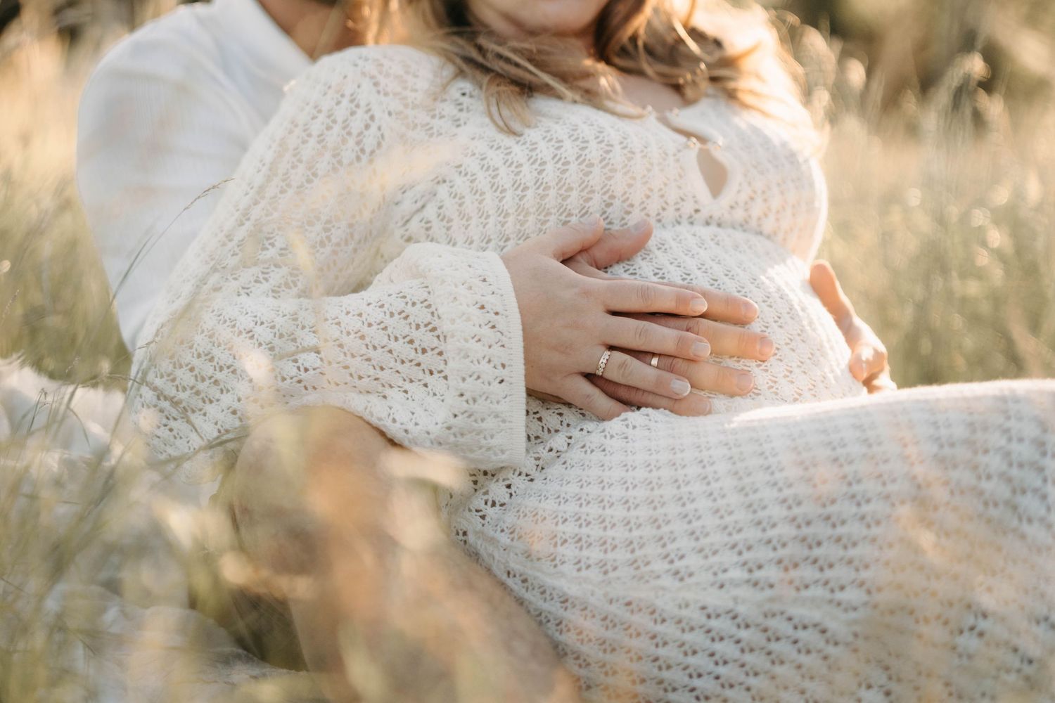 Babybauchfotos bei Sonnenlicht in der Wiese