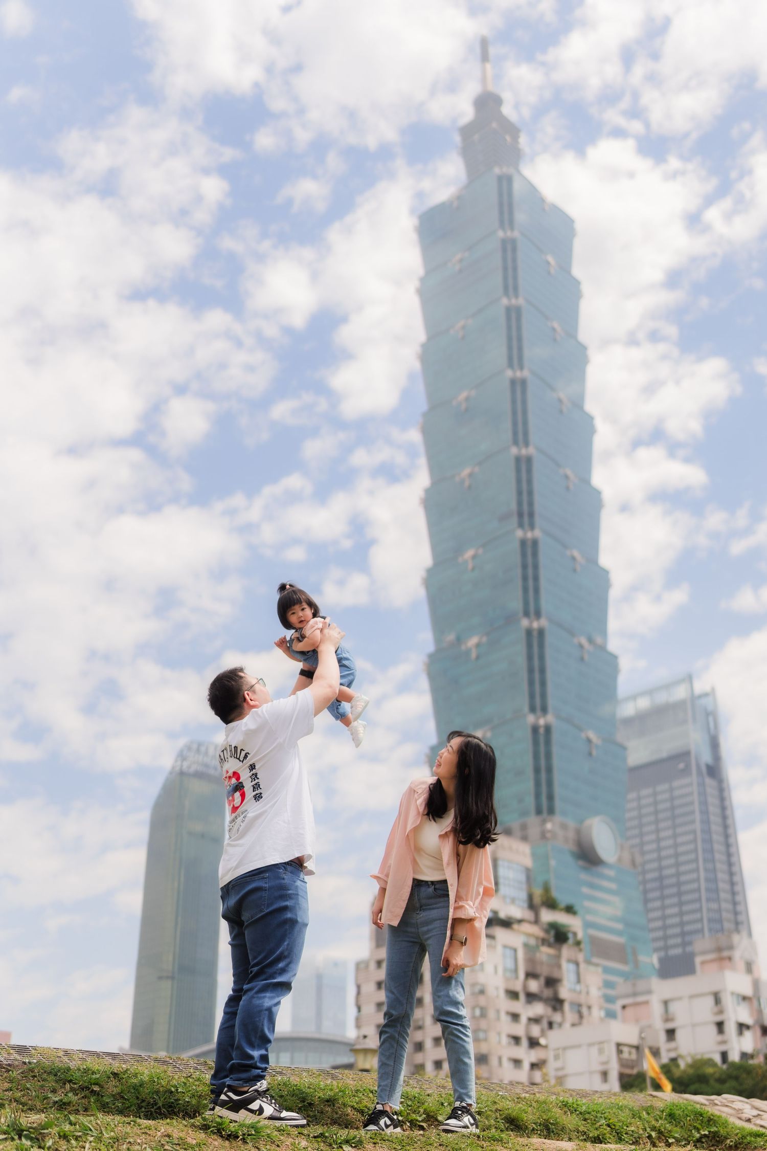 A series of photos showing a couple posing against the backdrop of Taipei 101 tower on a sunny day.