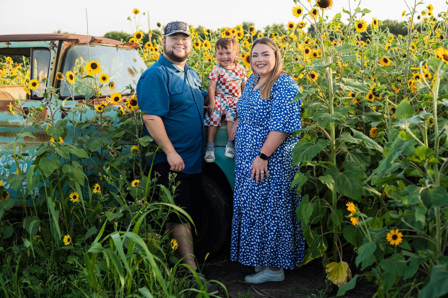 A family shares a joyful moment together at sunset by the water, all wearing casual dark clothing.