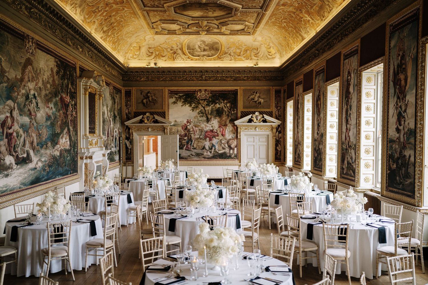 What is a booking fee. Elegant wedding reception setup in an ornate baroque palace hall with gilded ceilings and historic wall murals.