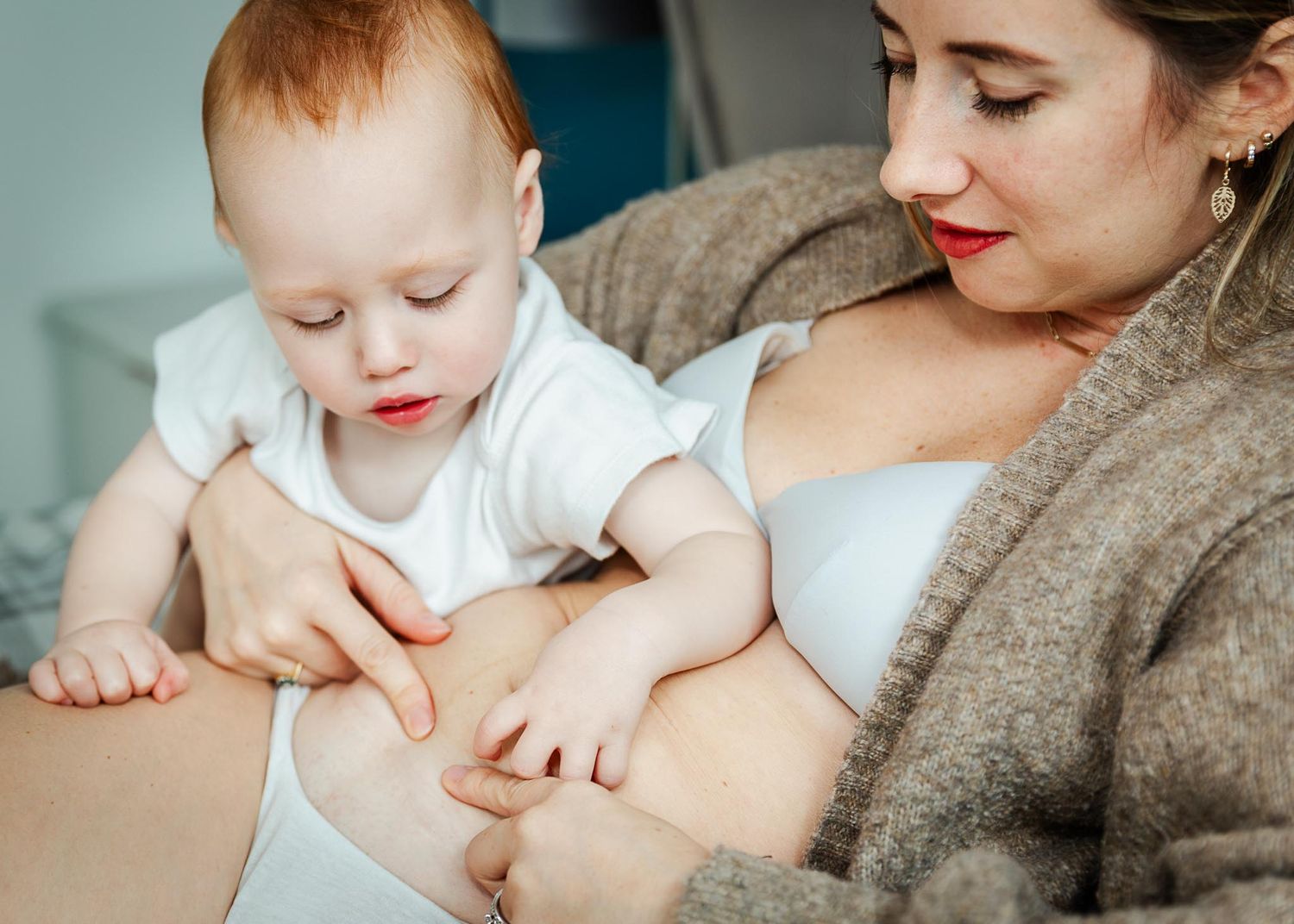 A toddler traces his mother's c-section scar as they cuddle on the bed at home. Caesarean awareness photos Bristol baby photographer
