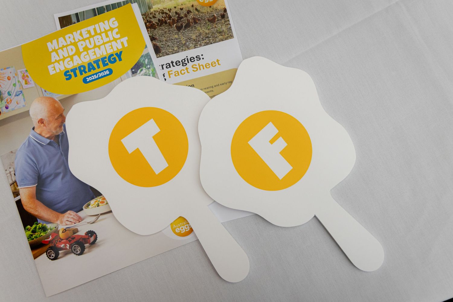 White cardboard signs with yellow speech bubble designs laid out on a gray surface.