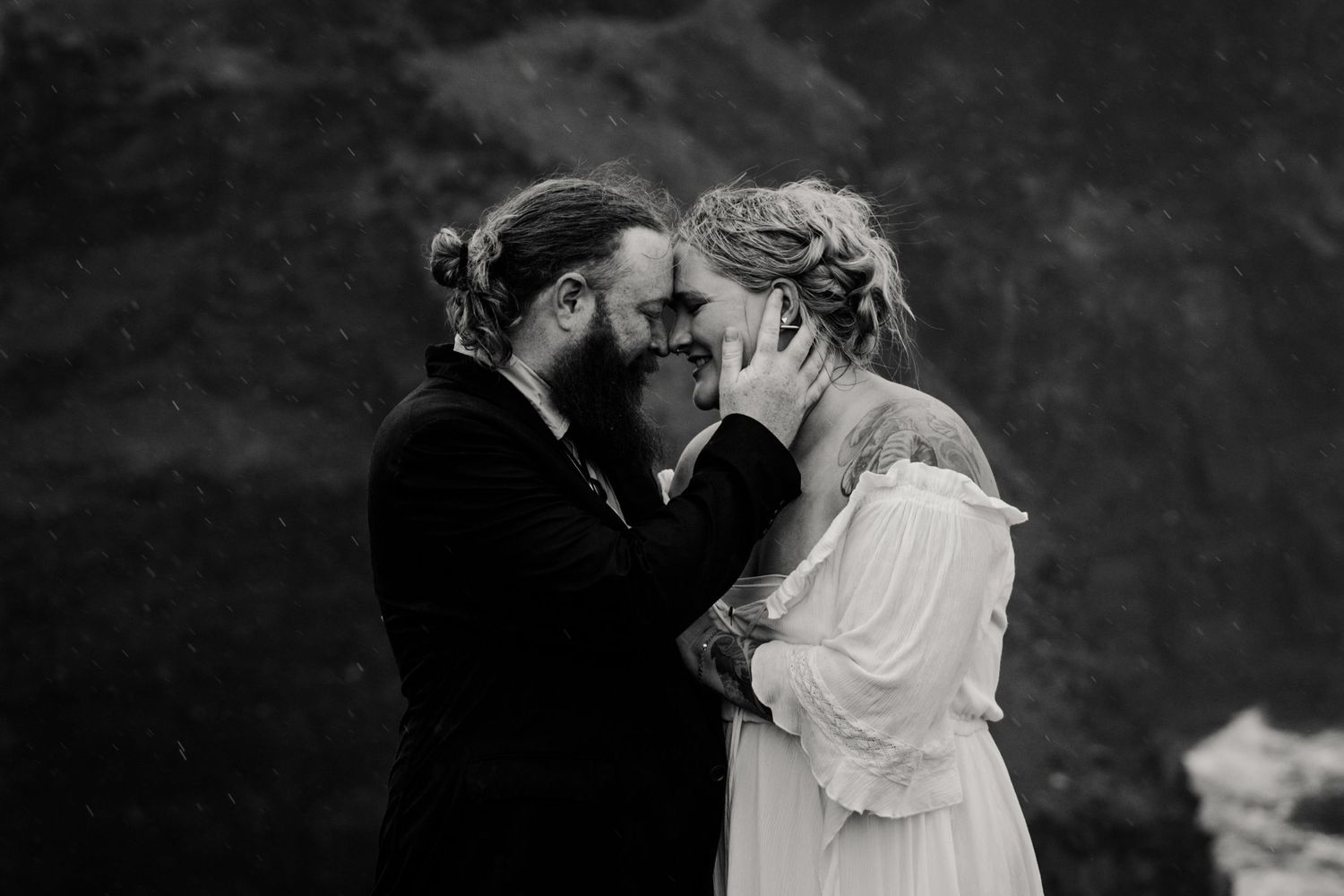 Couple embracing during moody rainy portraits at Hags Head Cliffs of Moher in Ireland at their elopement