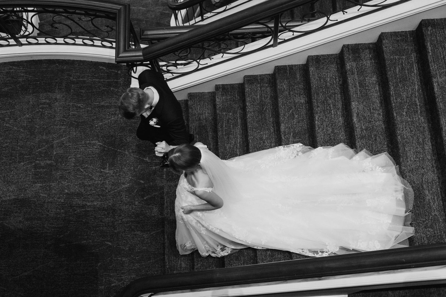 A bride in a white wedding dress lies gracefully on a staircase during a creative photoshoot.