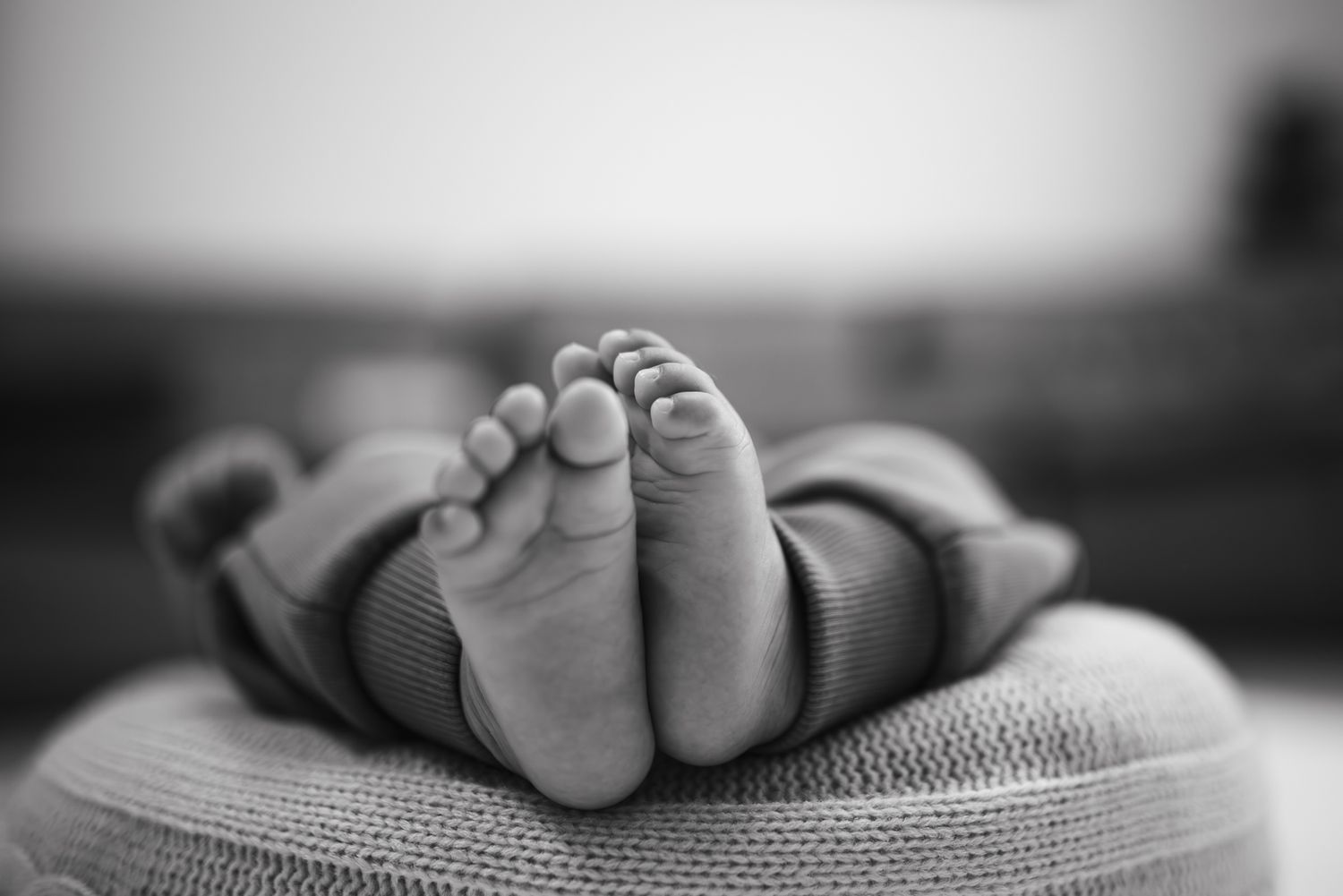 Black and white close-up photo of tiny newborn baby feet resting gently taken by a in-home Melbourne Newborn Photographer.