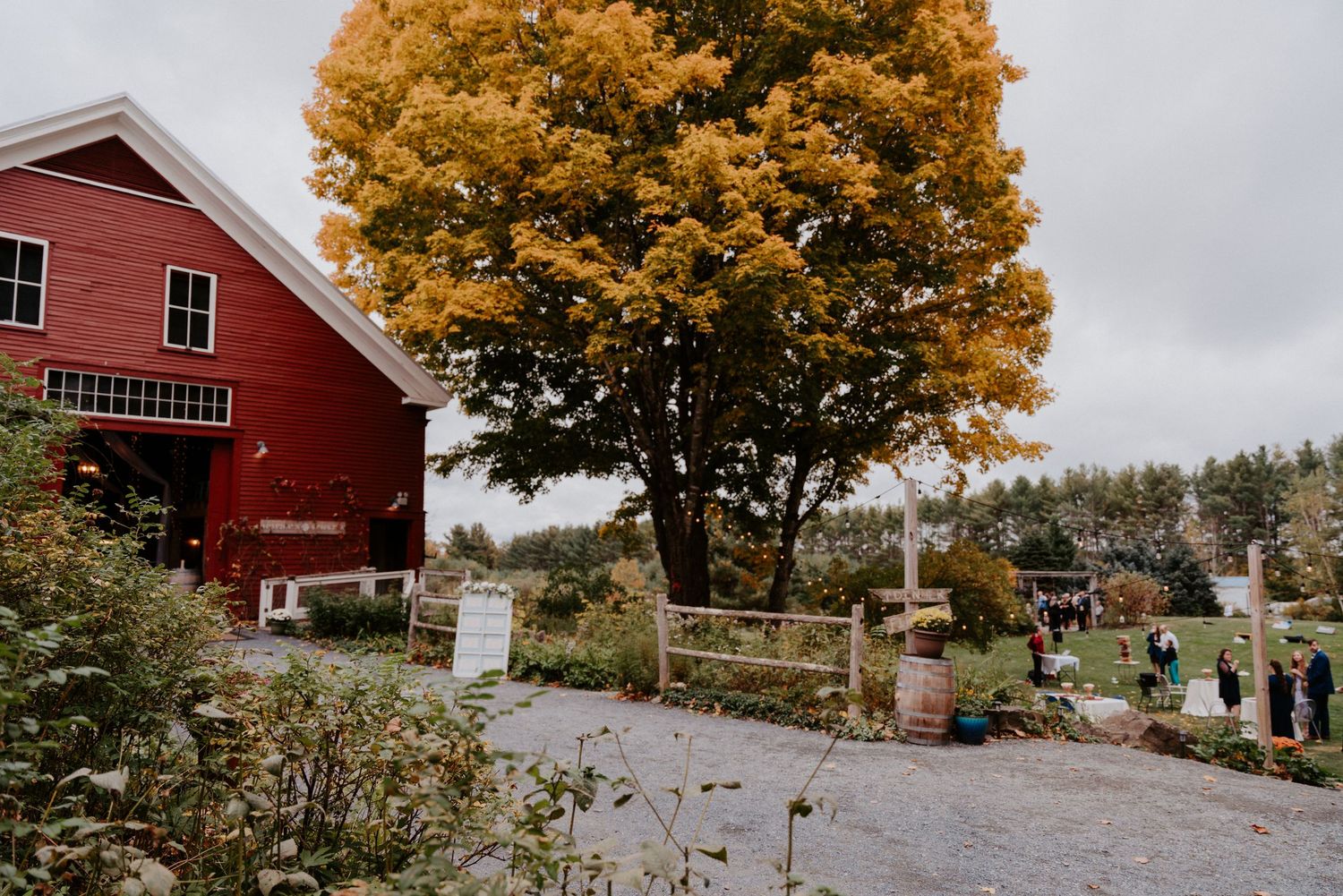 Autumn landscape with colorful orange and yellow trees surrounding a red farmhouse on a lush green lawn.