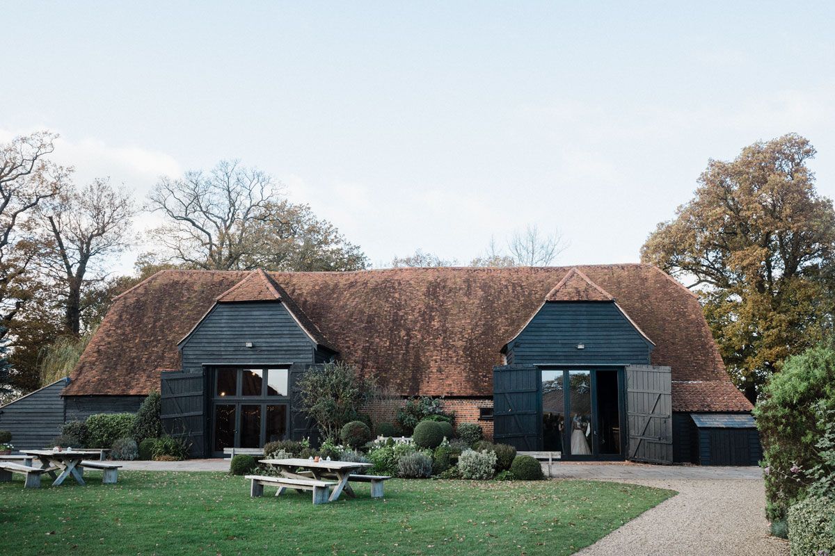 Rustic black barn wedding venue with traditional architecture and landscaped grounds.