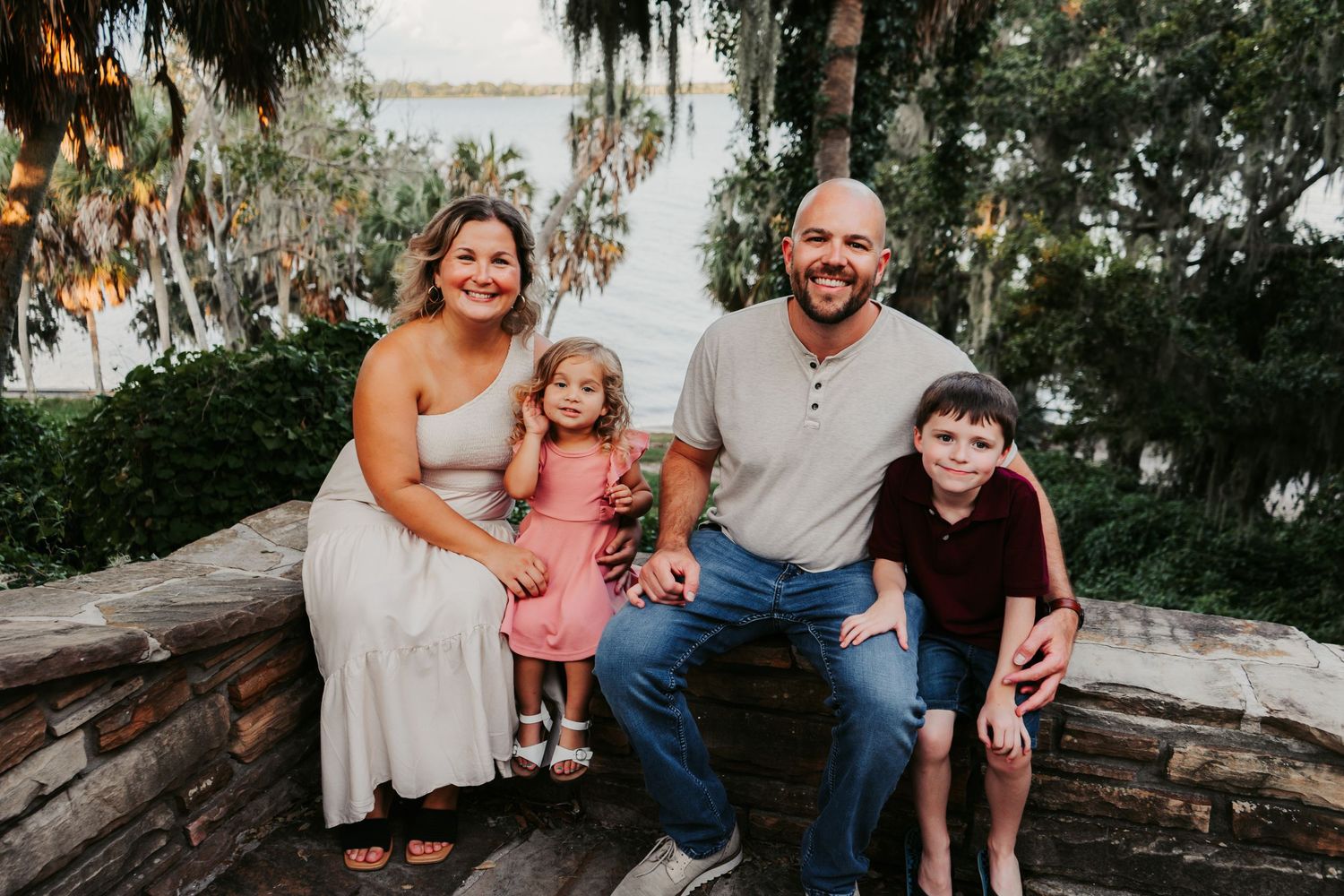 Outdoor Family Session Philippe Park in Safety Harbor, FL; family posing on stone wall overlooking water