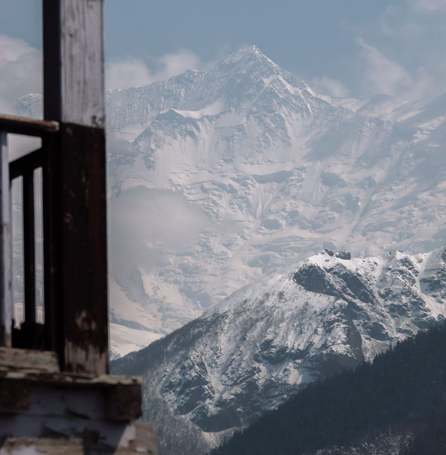 Snow-covered Himalayan peaks viewed through a window frame in crisp mountain air.