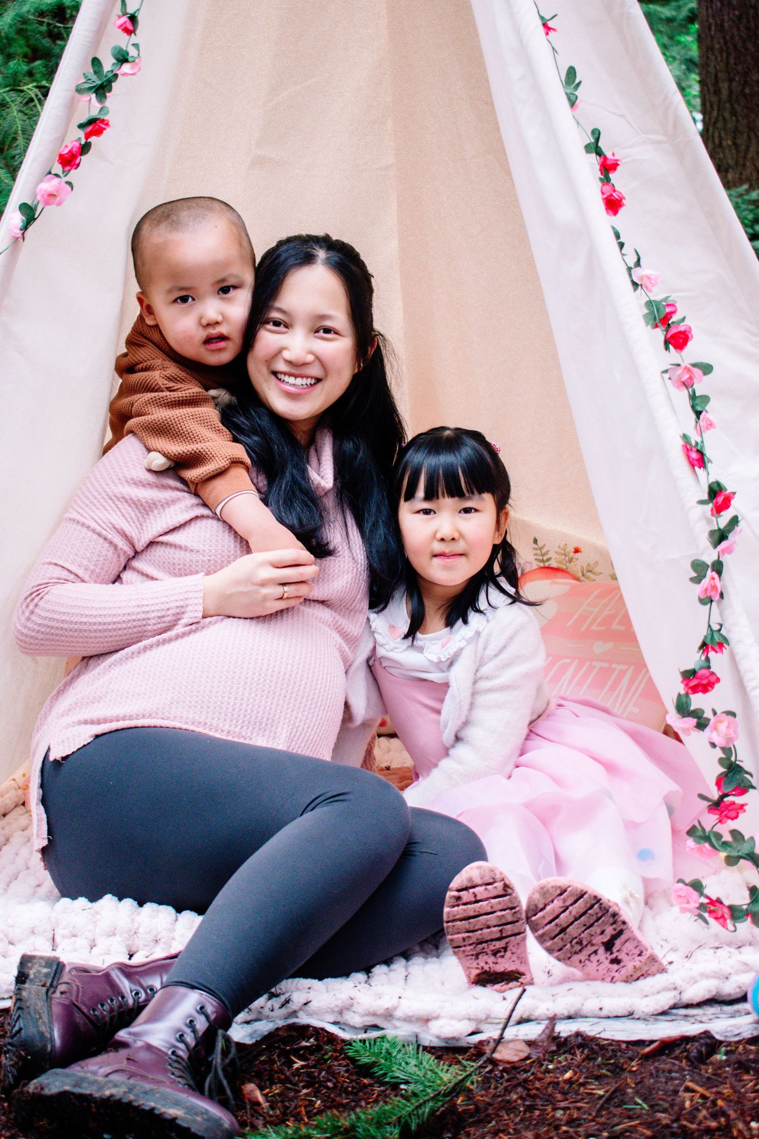 Mother with two children smiling inside floral tent during Mommy and Me mini session in Seattle