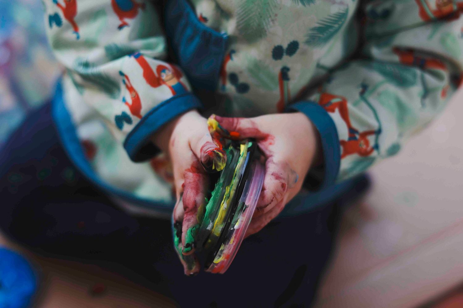 Hands holding a colorful sandwich filled with fresh vegetables and greens.