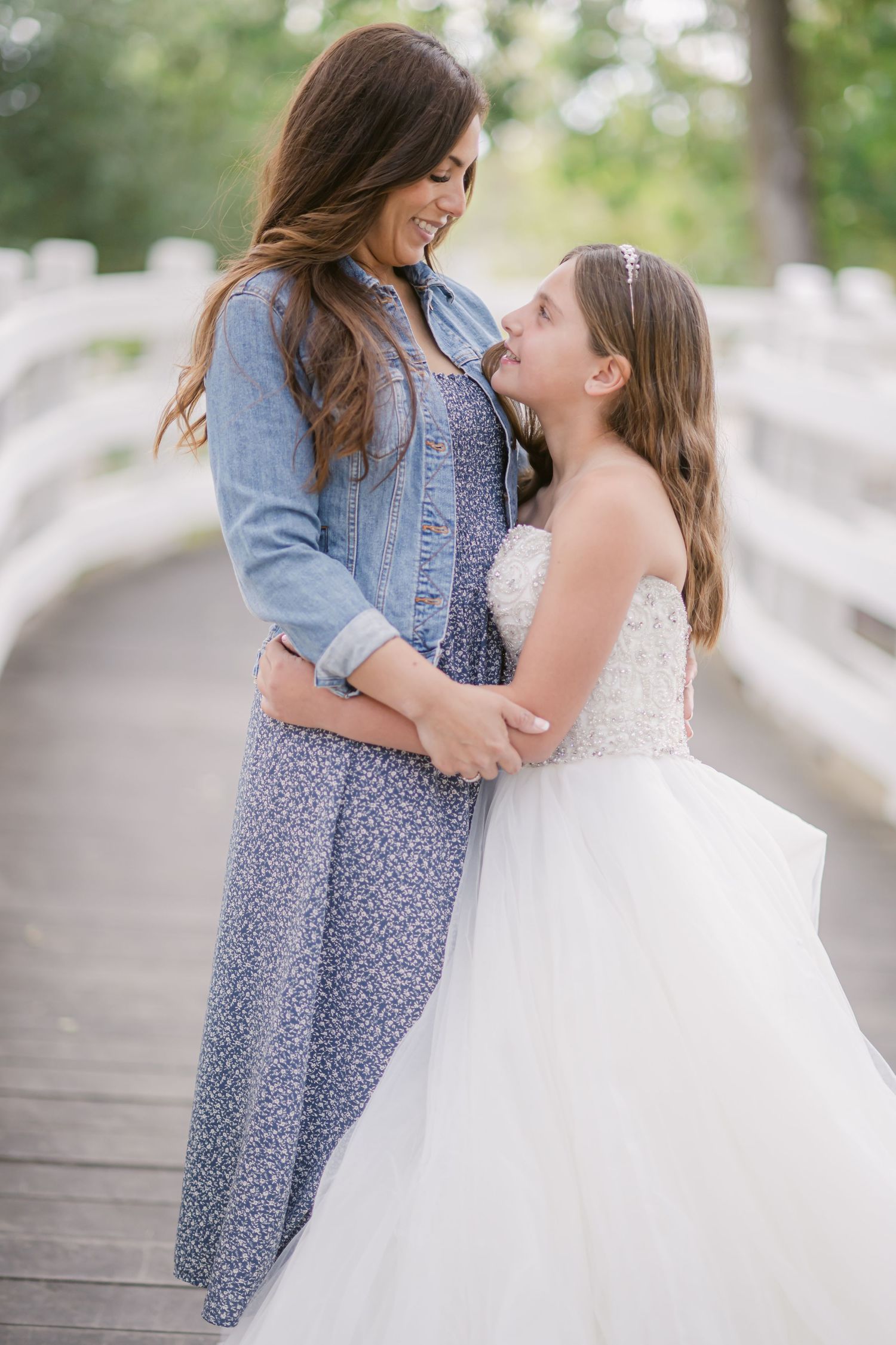 Two people share a tender embrace while wearing blue and white dresses in an outdoor setting with soft lighting.