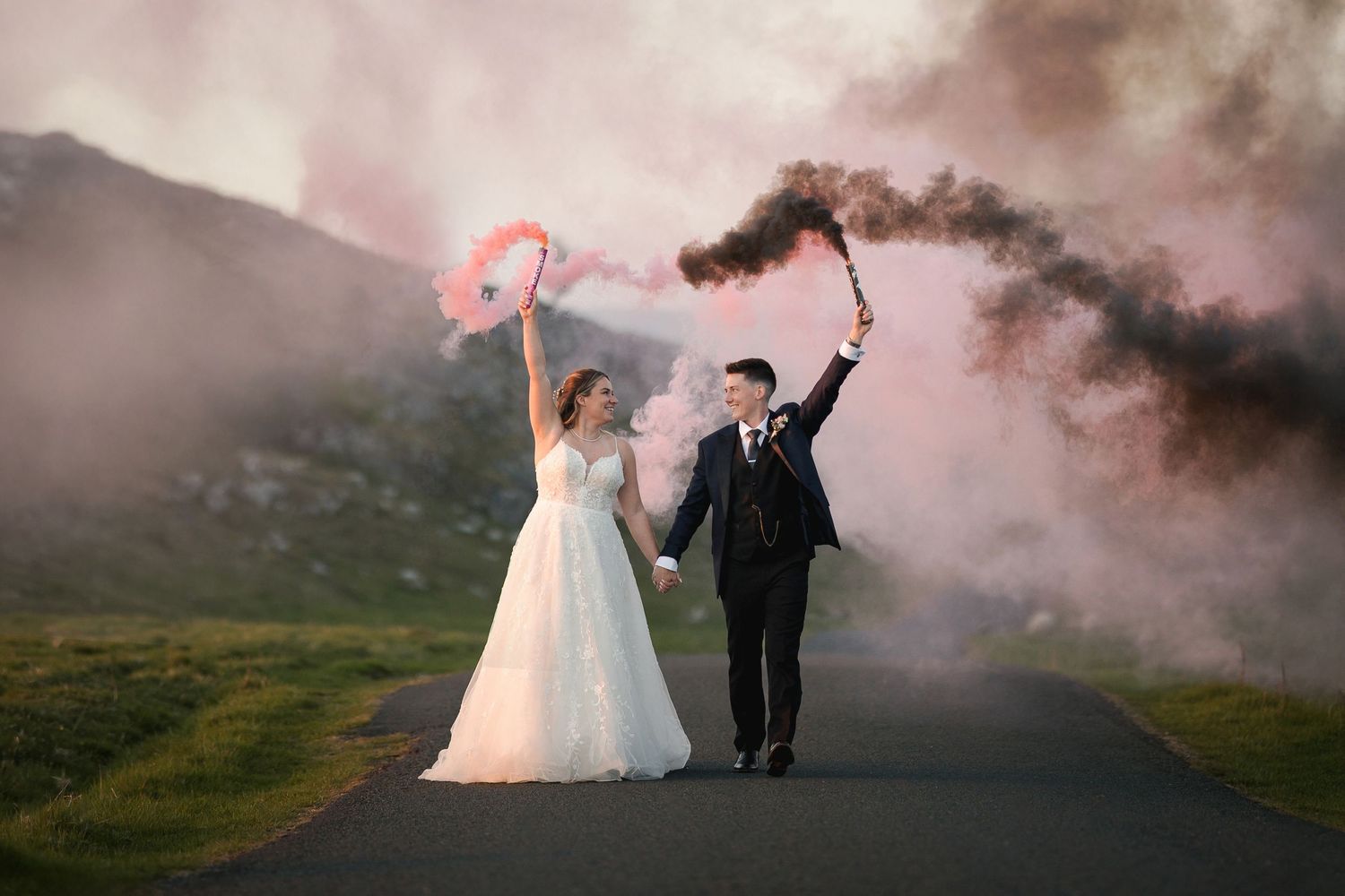 Wedding photos on a misty mountain road with a couple silhouetted against dramatic cloudy skies at sunset.