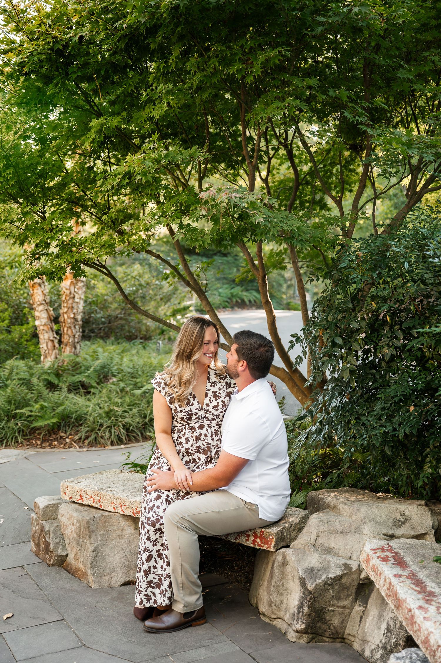 Couple sitting together on a stone bench in a peaceful garden setting.