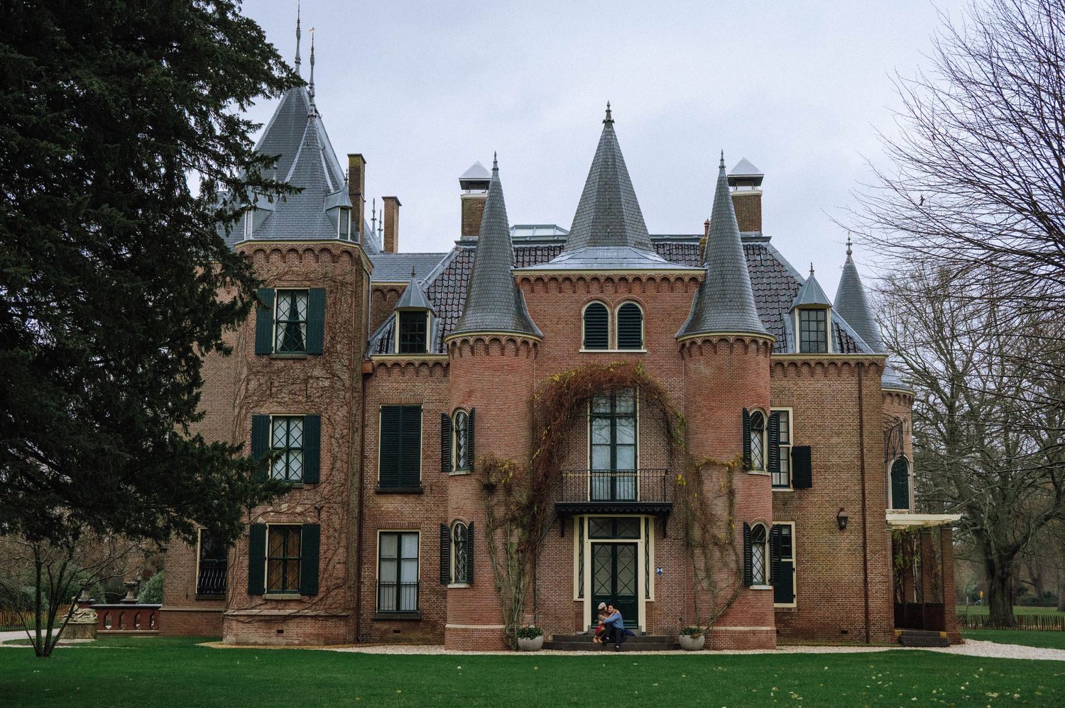 Couple sitting on the steps of a historic brick castle near Amsterdam during a romantic photoshoot