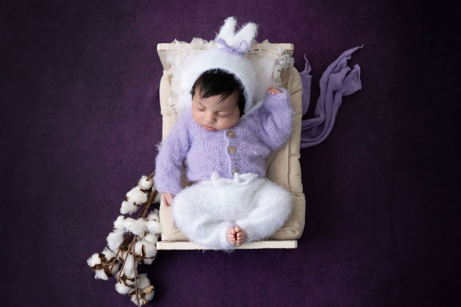 A newborn baby rests on white blankets in a series of professional black and white portraits.