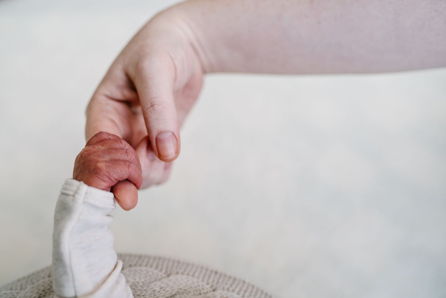 Close up shot of a newborn's tiny hands grabbing his mother's finger in white background taken by Melbourne newborn photographer.