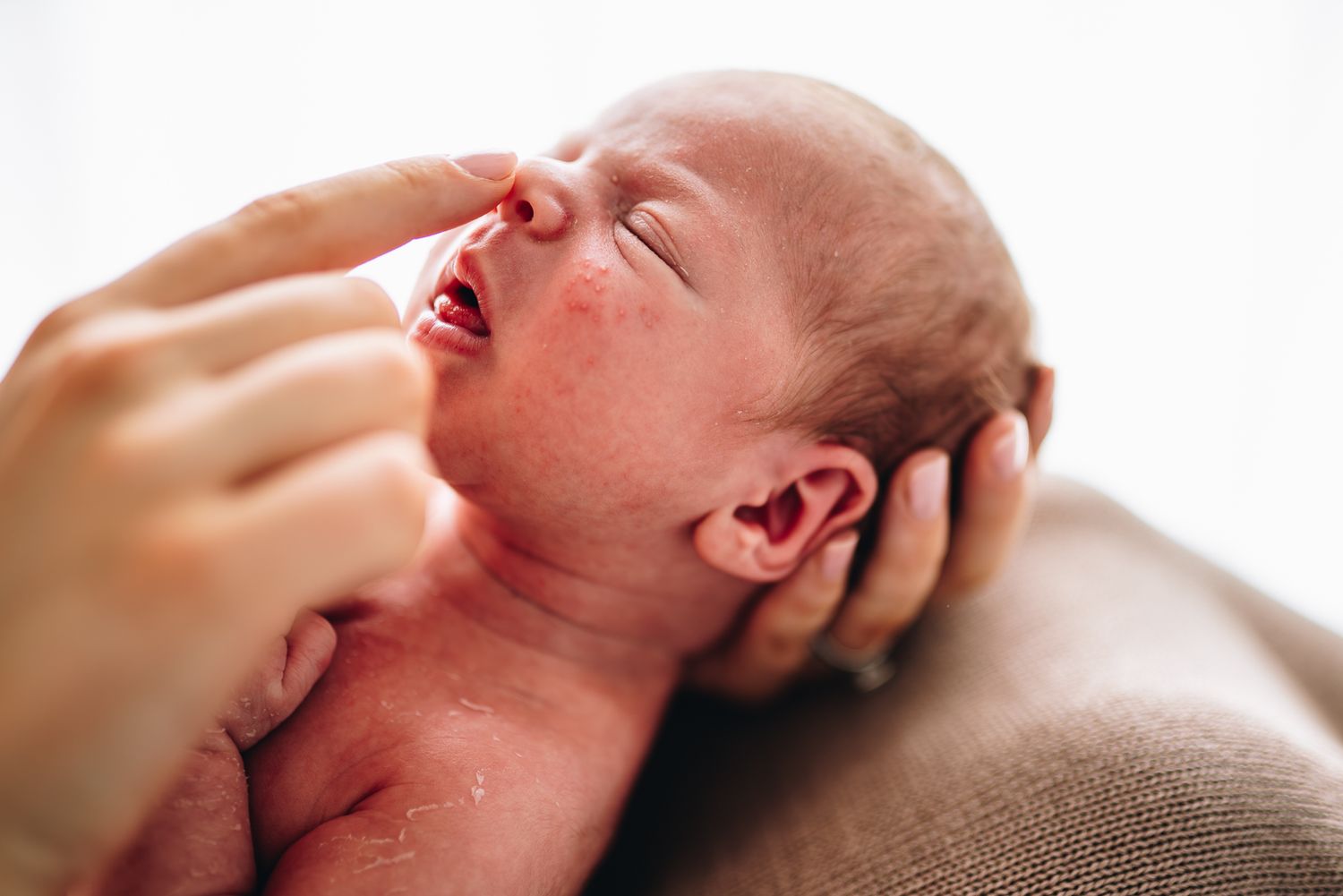 A sleeping baby with rosy cheeks rests peacefully in a soft blanket taken by Melbourne newborn photographer Pei A Photography.