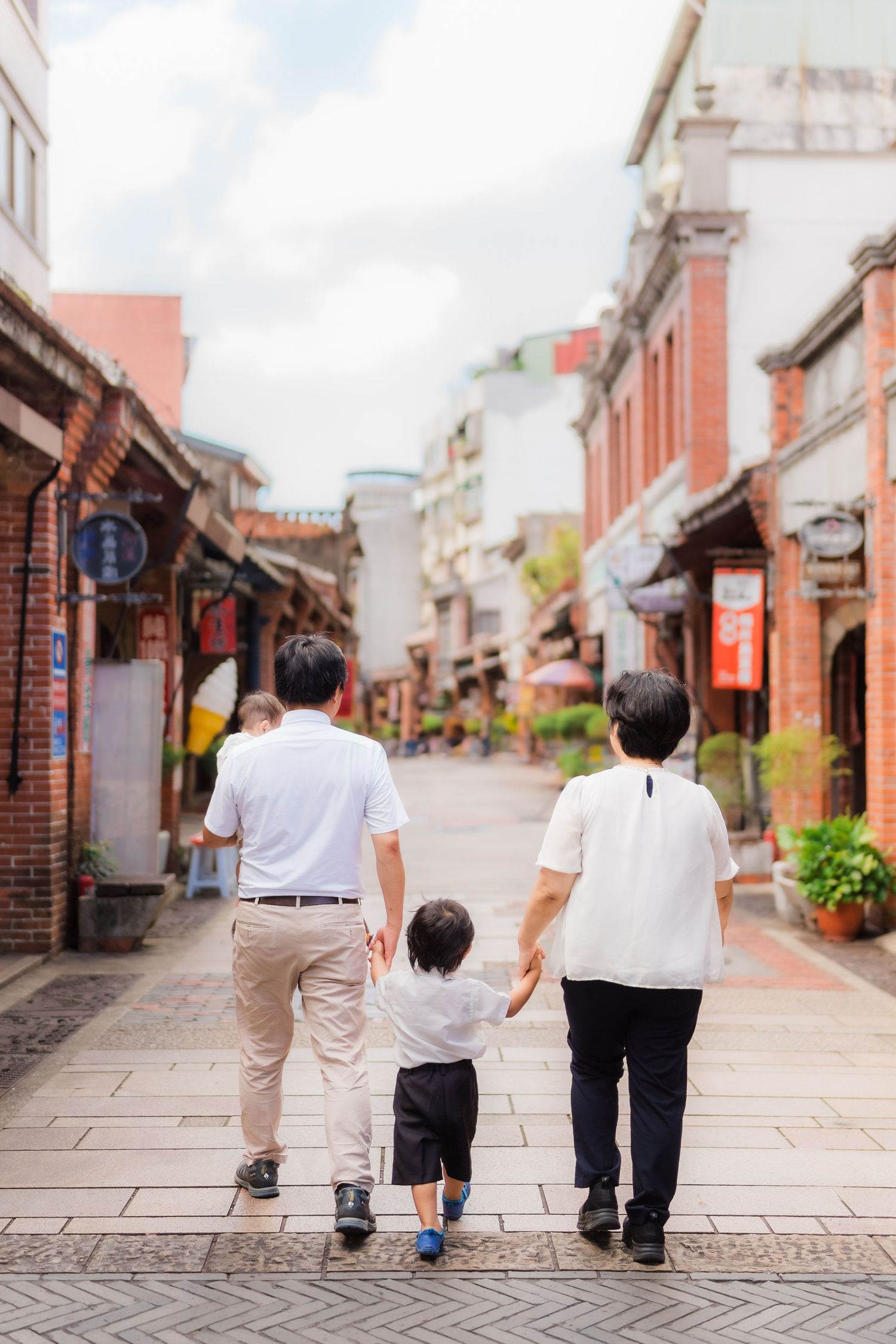 People walking together down a traditional stone-paved street lined with historic buildings and shops in Asia.