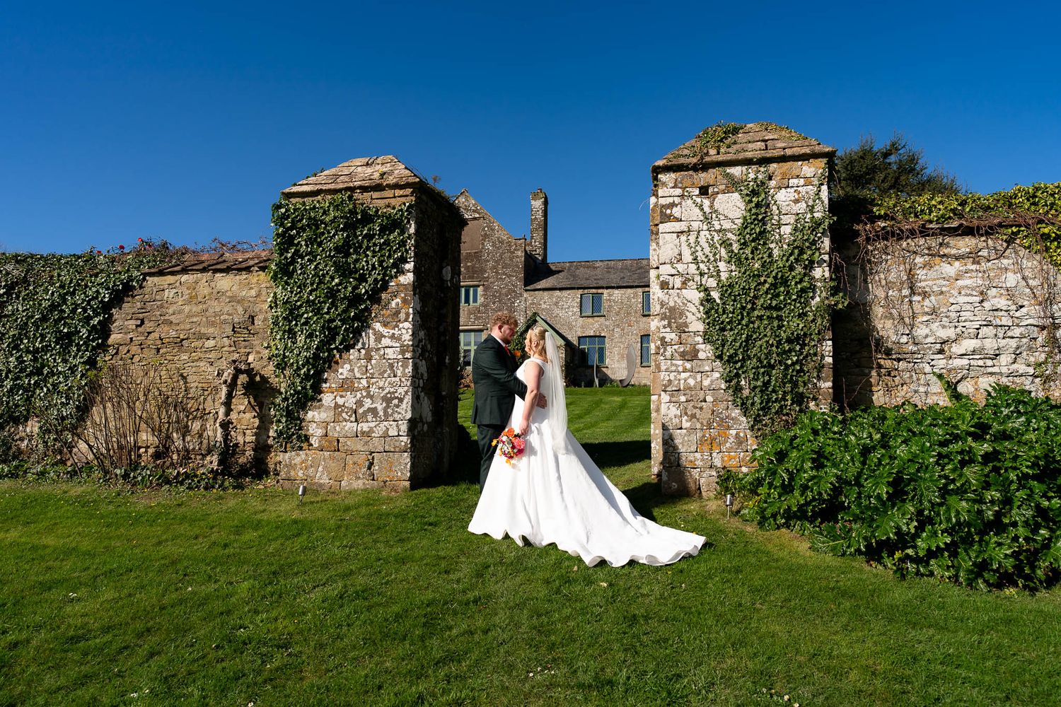 Newly married couple in front of rustic farm house at Ash Barton Estate in North Devon.