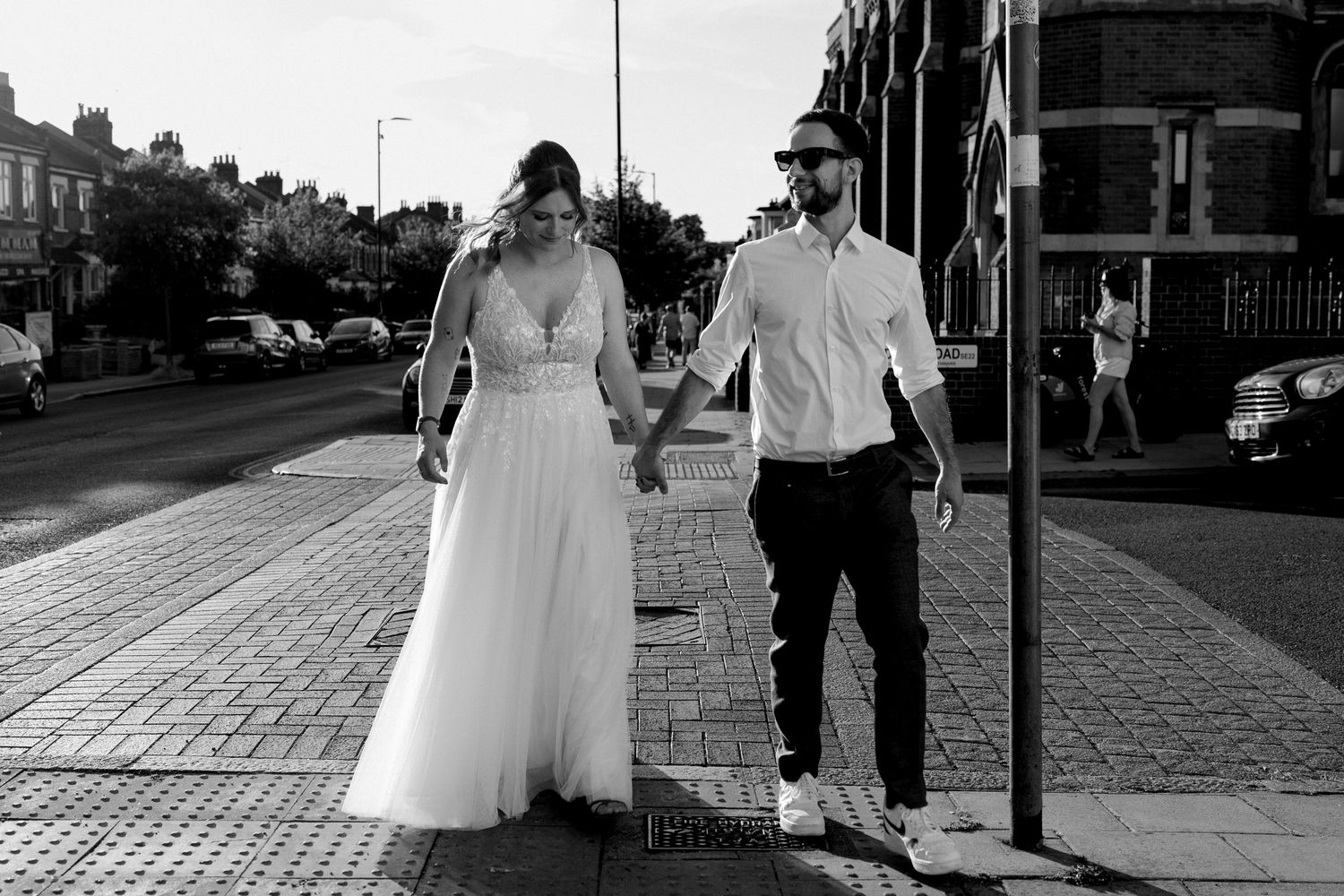 Wedding guests gather outside a brick building in formal attire on a sunny summer day.