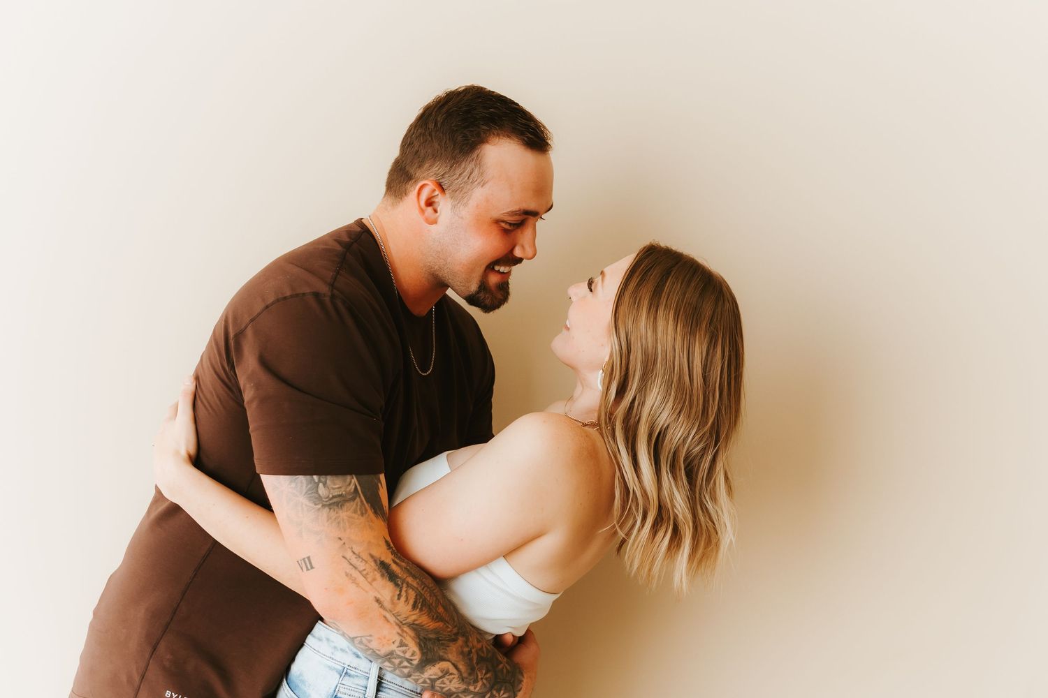 A romantic couple in an intimate dance pose against a light colored wall.