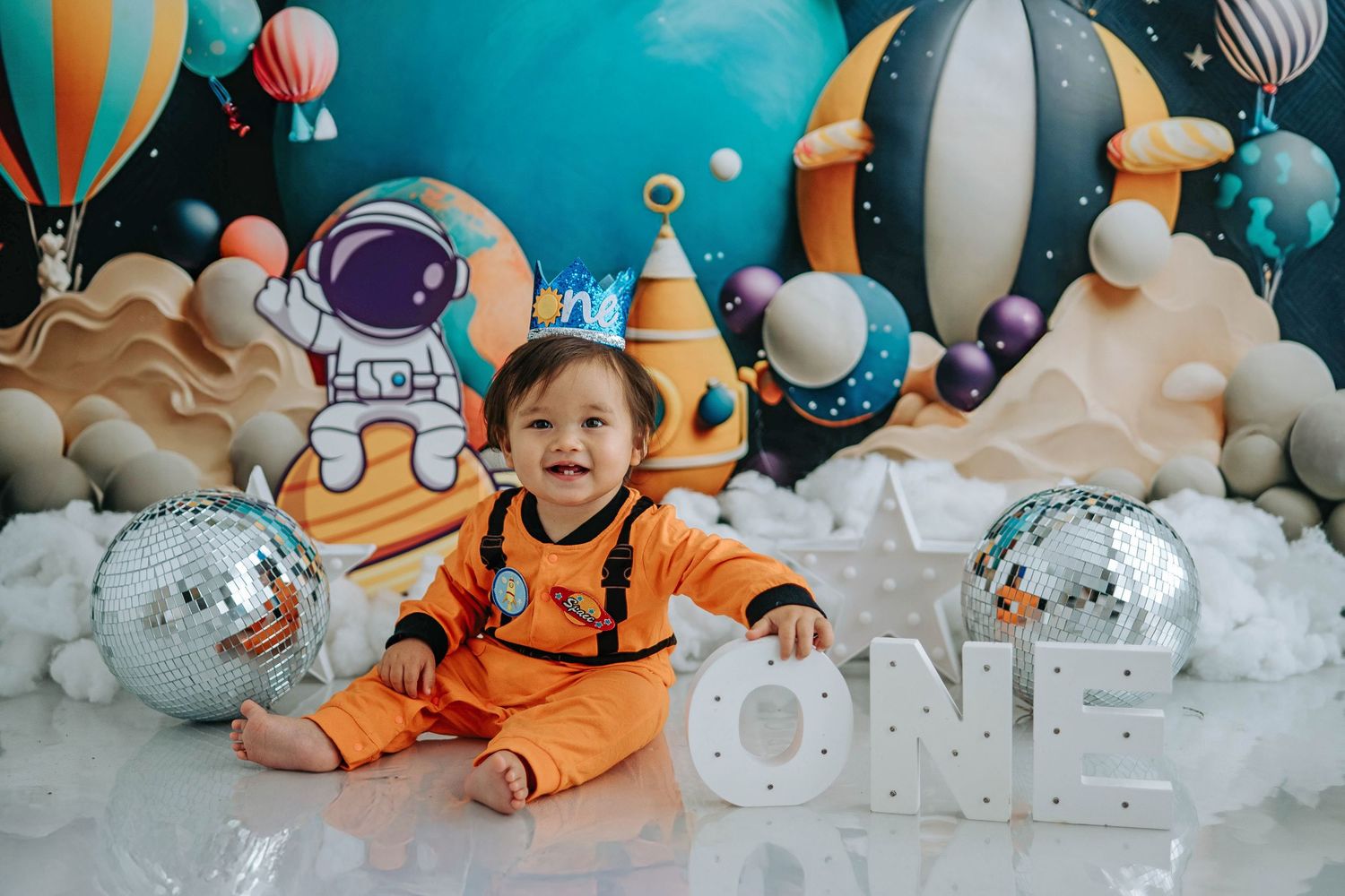 A series of space-themed first birthday party photos with astronaut decorations and cotton cloud displays.