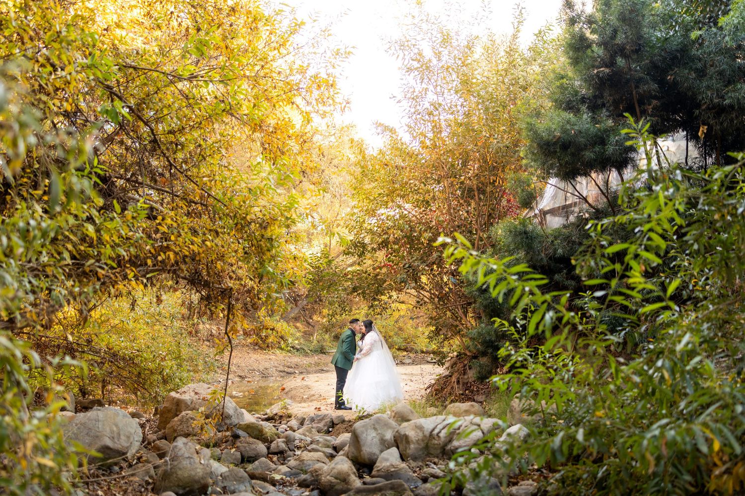 A tender moment between newlyweds posing against a white wall.