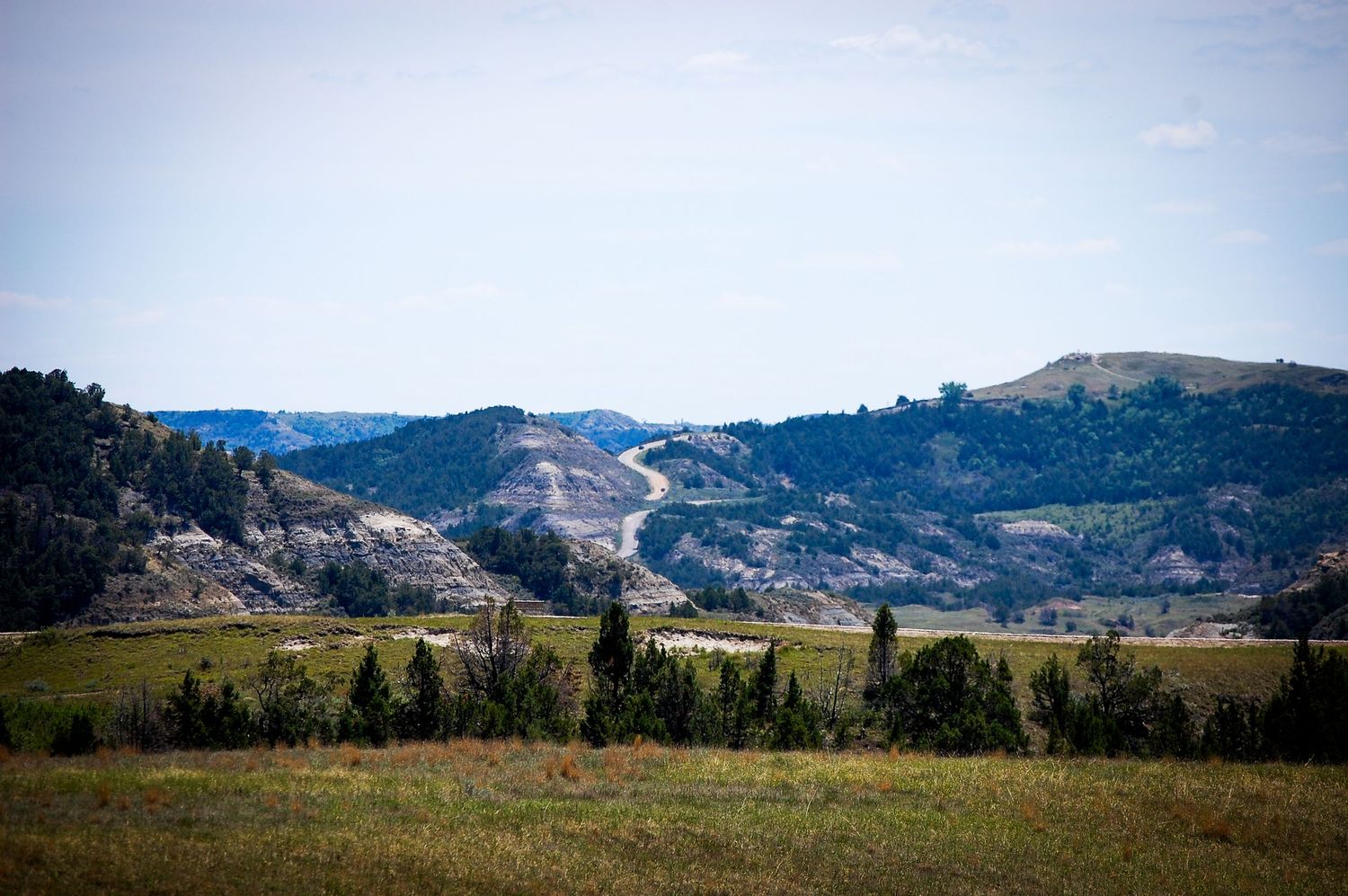 A panoramic view of rocky mountain terrain with sparse vegetation and rugged cliffs stretching across the horizon.