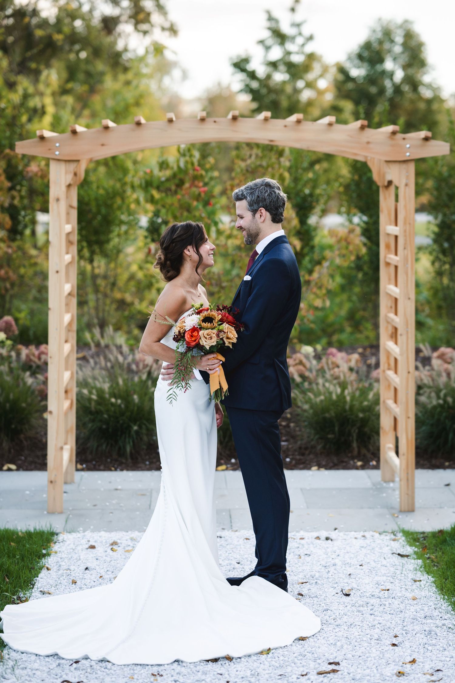 Hudson Valley, NY wedding couple exit outdoor ceremony up lawn aisle with fall foliage and stone arches at sunset at Brotherhood Winery.