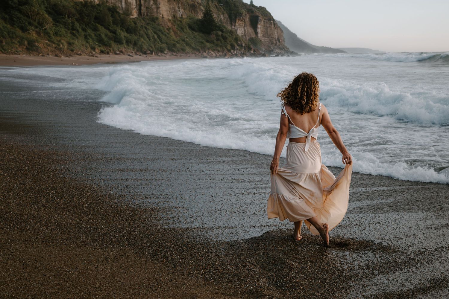 A collection of scenic coastal images showing waves crashing on a black sand beach at sunset with cliffs in the distance.