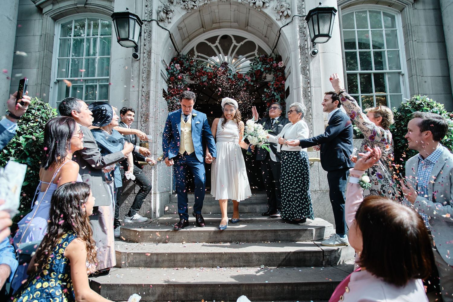 Wedding guests throw confetti on stone steps outside Chelsea Town Hall.