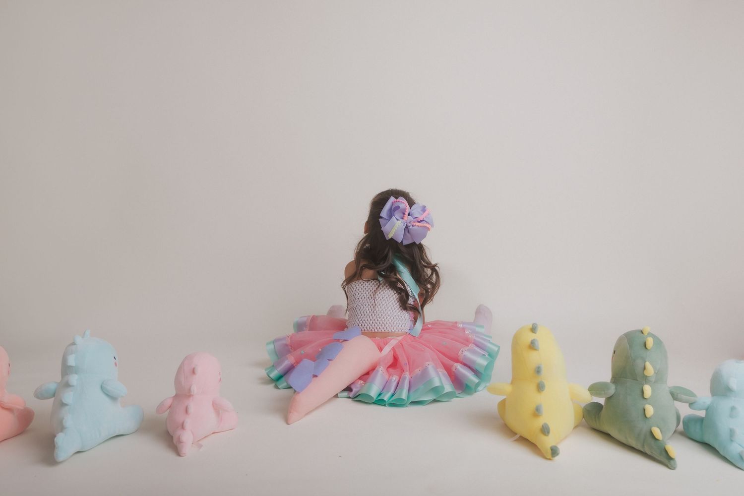 A pastel birthday setup with colorful dinosaur decorations and tulle dress details.